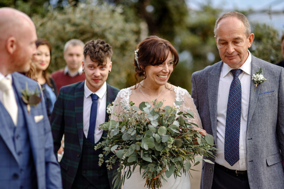 Cheryl walking down the aisle with her father inside the Mediterranean Biome